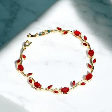 Gold bracelet with red stones on a marble surface