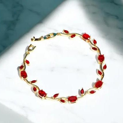 Gold bracelet with red stones on a marble surface