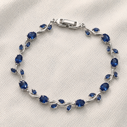Silver bracelet with blue gemstones on a white fabric background