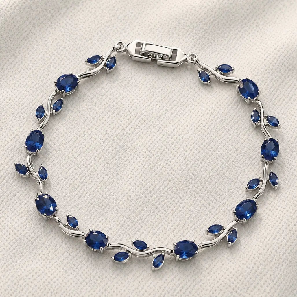 Silver bracelet with blue gemstones on a white fabric background