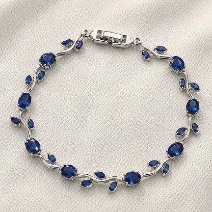Silver bracelet with blue gemstones on a white fabric background