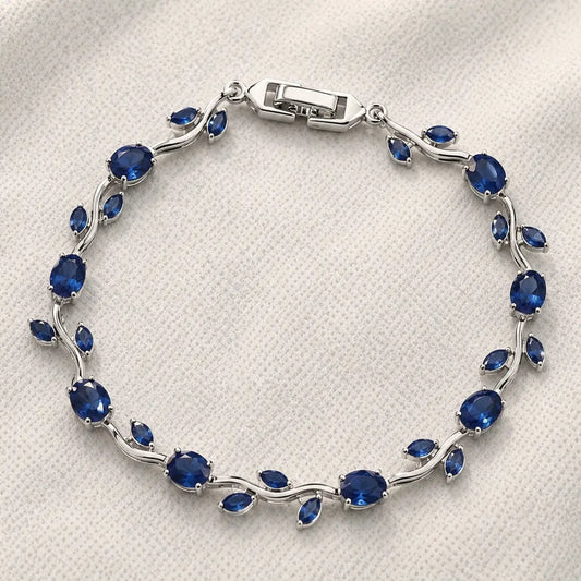 Silver bracelet with blue gemstones on a white fabric background